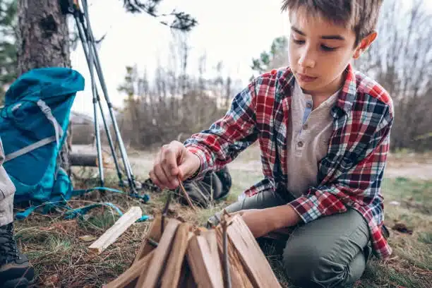 Niño haciendo una pequeña hoguera en el campo