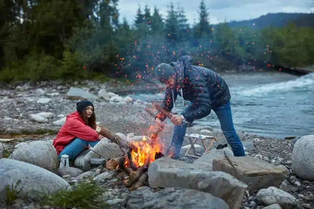 Pareja haciendo una hoguera en la naturaleza